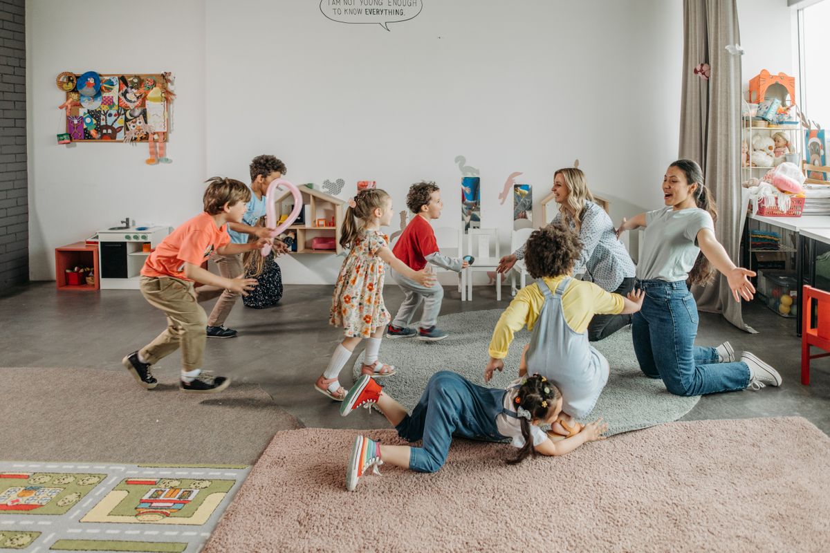 Éducatrice de jeunes enfants jouant avec plusieurs bébés dans une crèche lumineuse