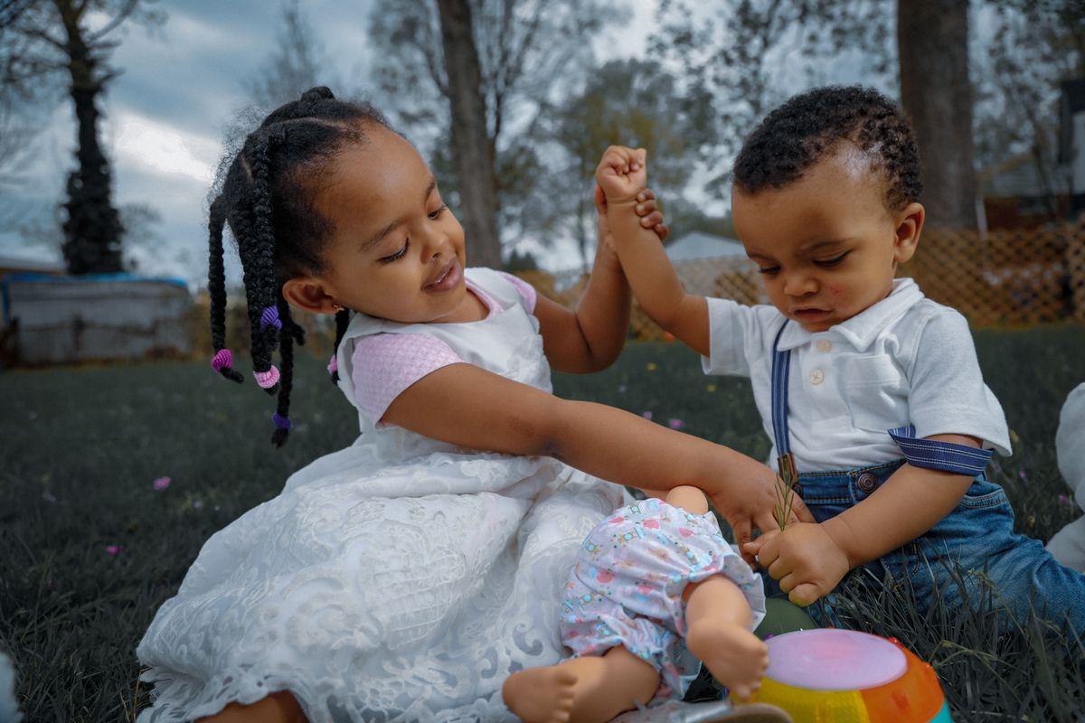 Deux enfants d'âges différents jouant ensemble dans un jardin ensoleillé