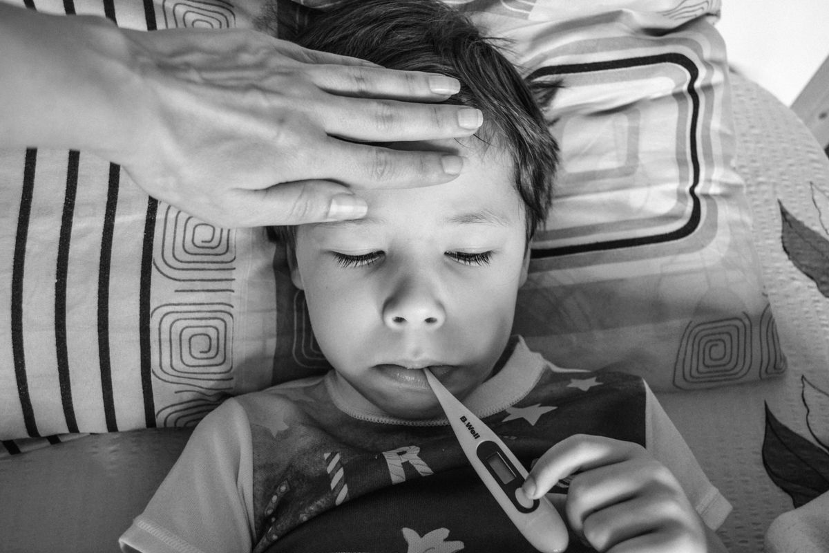 Parent prenant la température d'un enfant malade allongé avec un thermomètre auriculaire