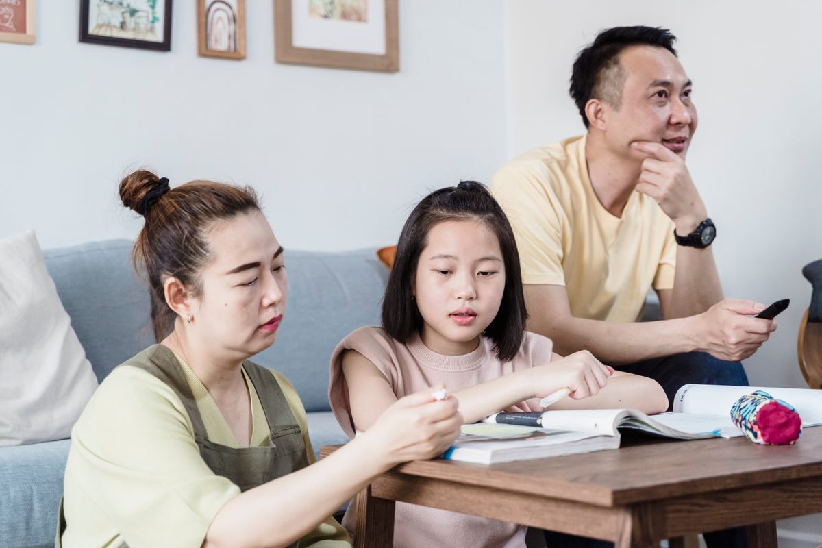 Parent assis à côté de son enfant regardant ensemble un bulletin scolaire avec bienveillance